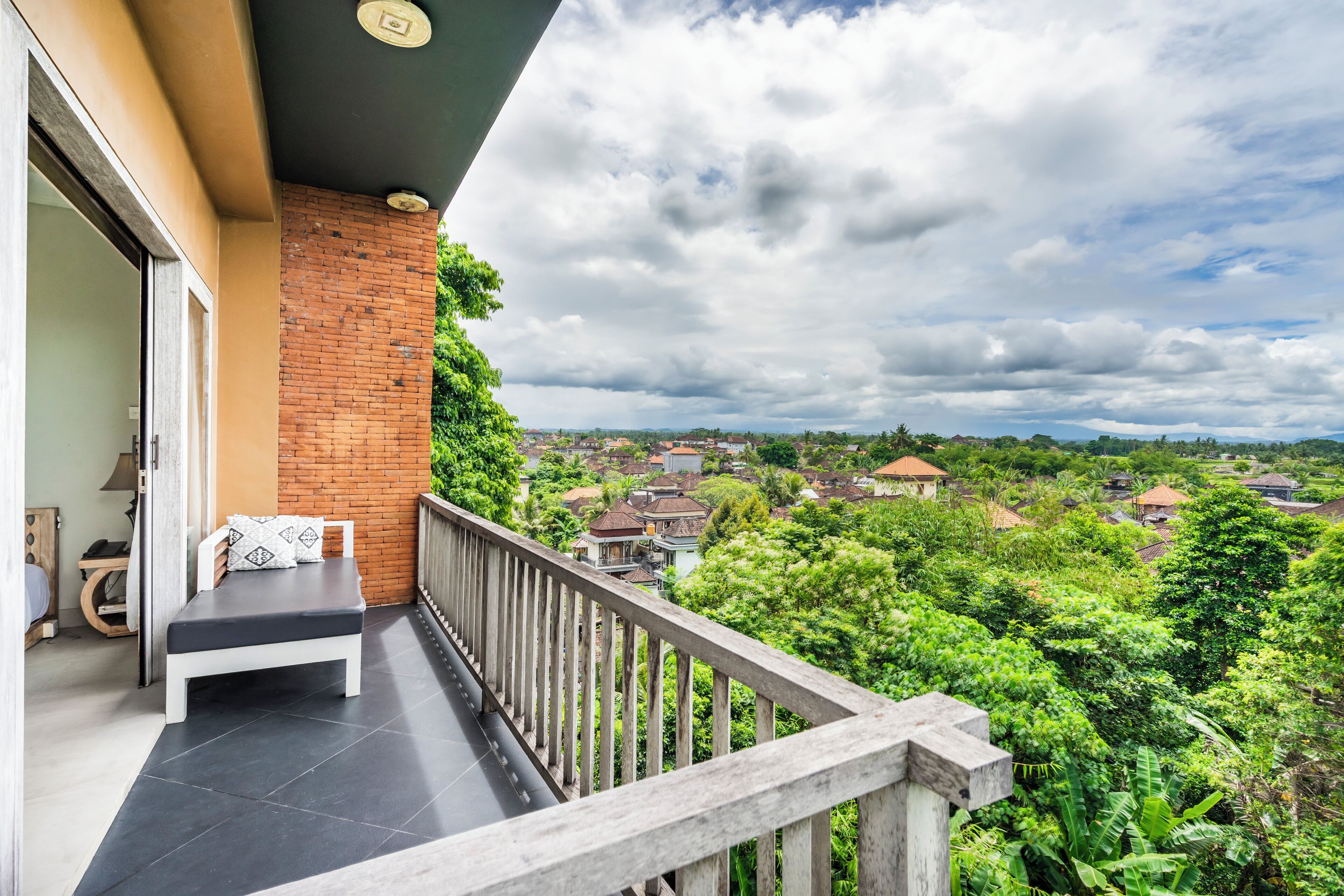 Un balcón con banca y vista a una zona residencial.