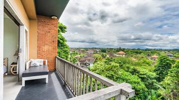 Un balcón con banca y vista a una zona residencial.