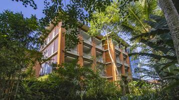 A multi-story building with balconies, surrounded by dense tropical vegetation.