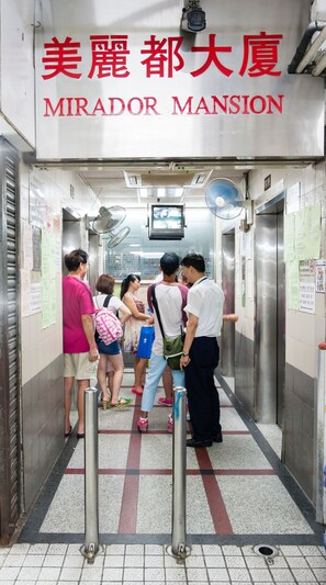 A group of people standing in an elevator at the entrance of a building with a sign reading "Mirador Mansion". - Lily Garden Guest House (Kowloon)