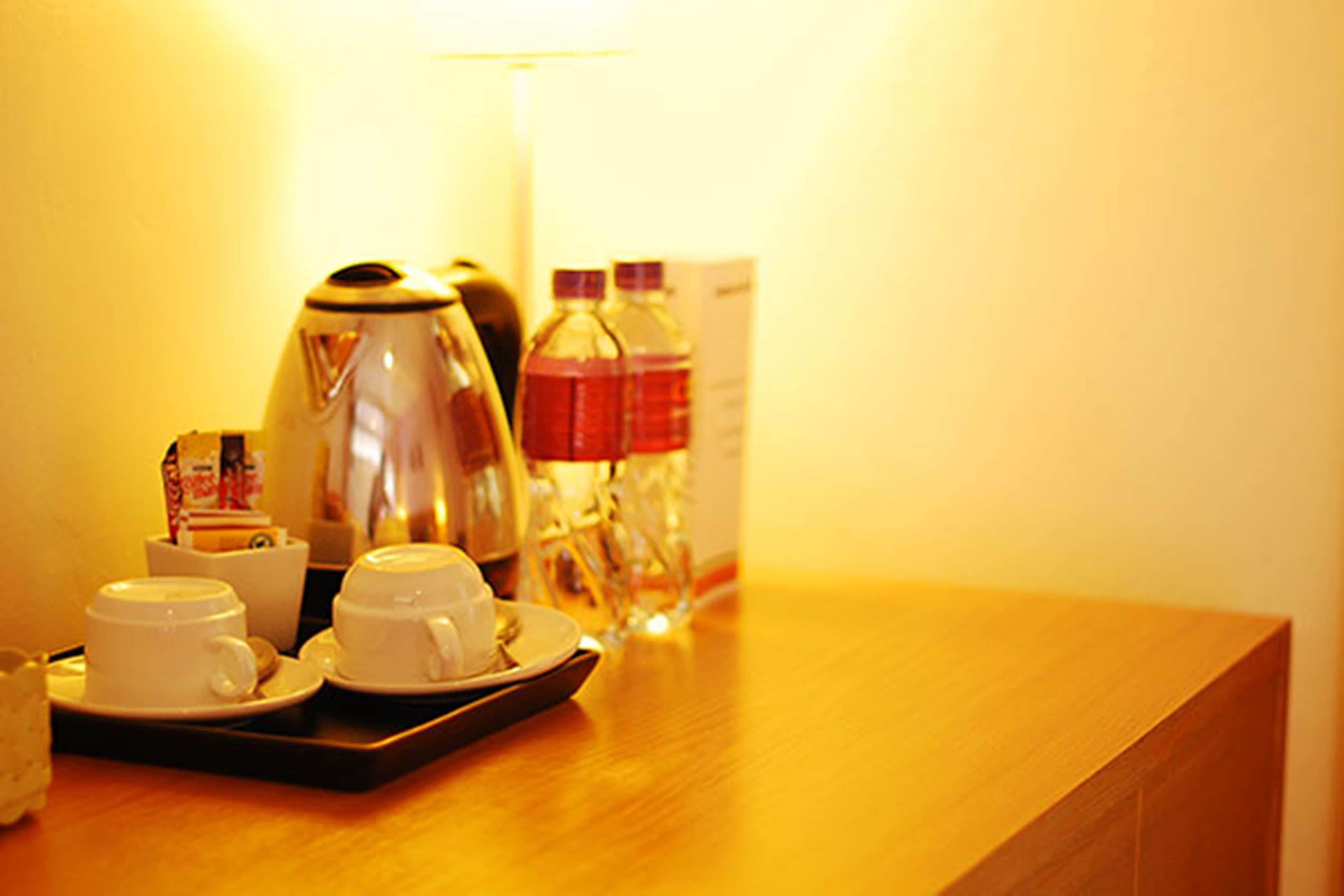 A tray with two white cups and saucers, a small container, and a glass carafe on a wooden table.