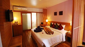 A hotel room with a bed, bedside table, lamp, and a television on the wall. - The Embassy Sathorn (Bangkok)