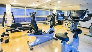 A gym with various exercise equipment, including treadmills and weight machines, and a large mirror reflecting the space. - The Embassy Sathorn (Bangkok)