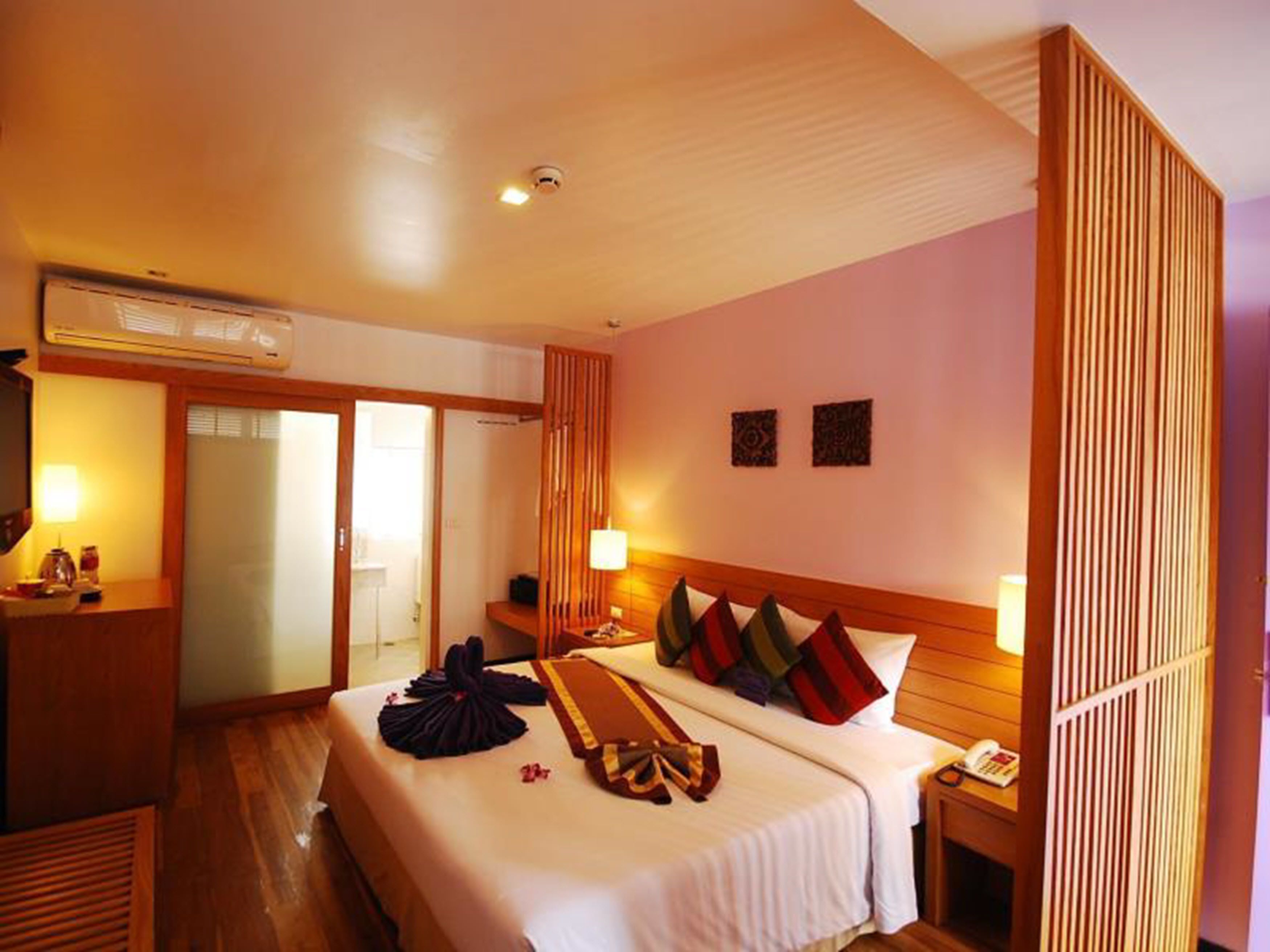 Une chambre d’hôtel comprenant un lit, une table de chevet, une lampe et une porte coulissante donnant sur une salle de bain.
