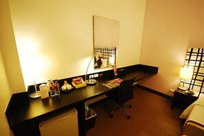 A hotel room with a desk, chair, bedside table, lamp, and a bed. - The Embassy Sathorn (Bangkok)