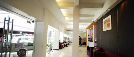 A spacious lobby with a glass entrance, a reception desk, and a seating area with a red couch.