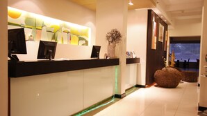 A reception area with a modern design, featuring a reception desk, a large abstract painting, and a decorative vase. - The Embassy Sathorn (Bangkok)