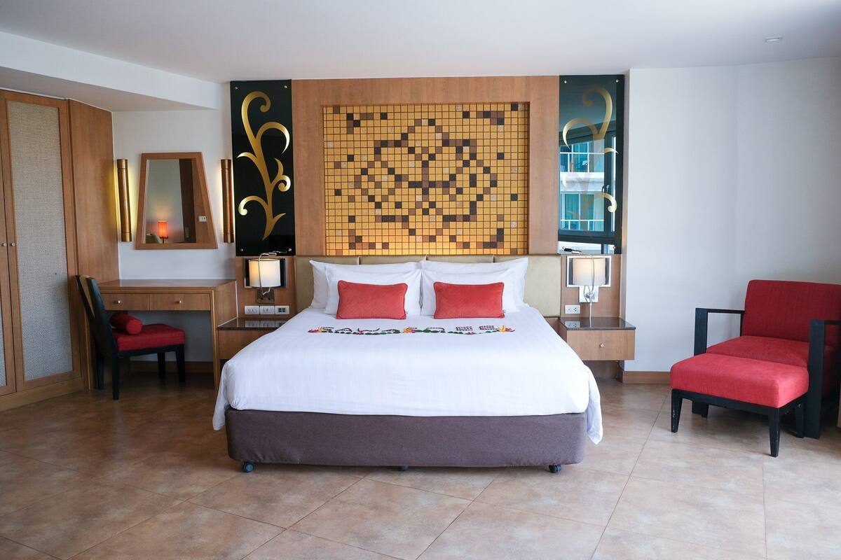 Habitación de hotel con una cama grande, un escritorio, una silla y un panel decorativo en la pared.