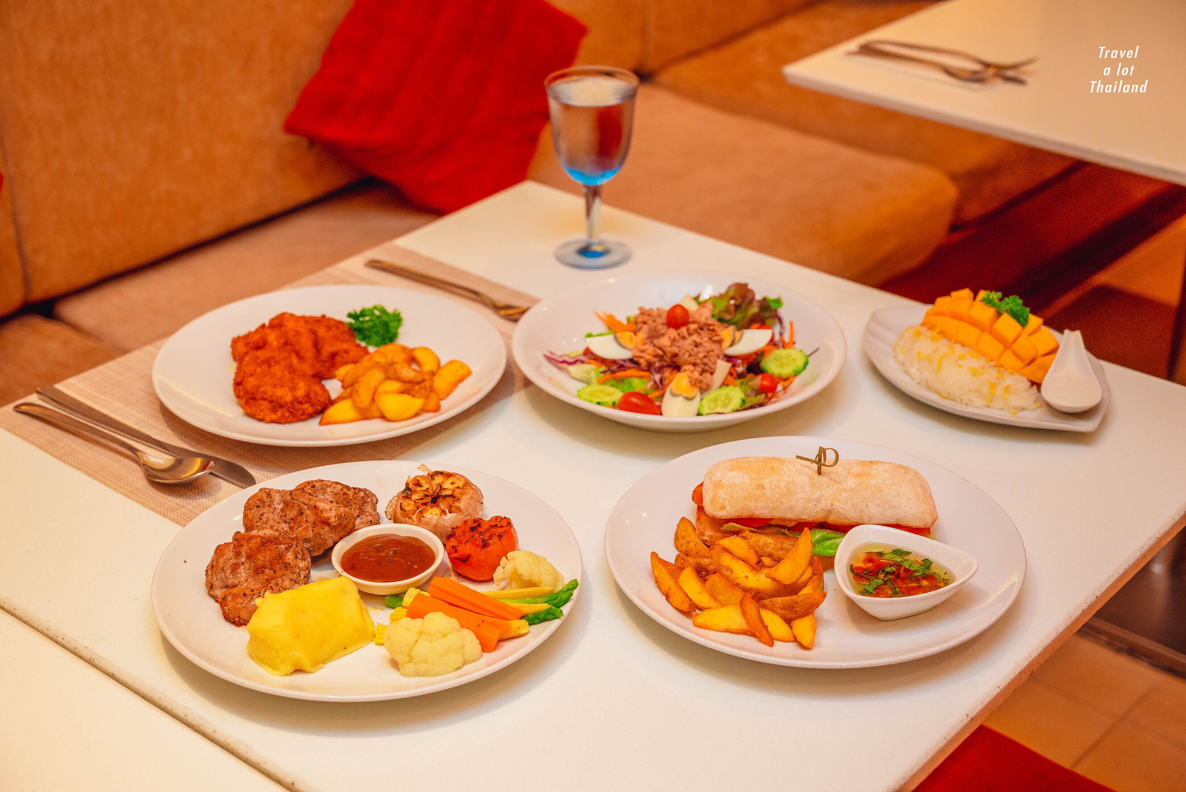 A table with various dishes including fried chicken, salad, and a wrap.