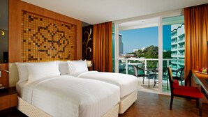Hotelkamer met een groot bed, uitzicht op de stad en een balkon met een stoel.