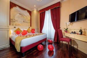 Una camera d'albergo con un letto grande, tende rosse e bianche, una scrivania con una sedia e una televisione a schermo piatto.