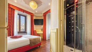 A hotel room with a bed, a desk, a TV, and a shower area.