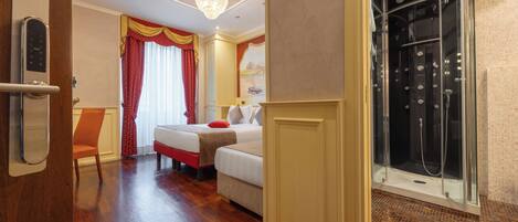 A hotel room with a wooden floor, a bed with red and white bedding, a chair, a shower with glass doors, and a chandelier.