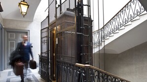 A man walking down a corridor with a staircase to the right.