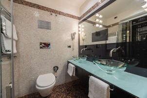 Un bagno moderno con un lavandino in vetro, un WC e uno specchio grande.