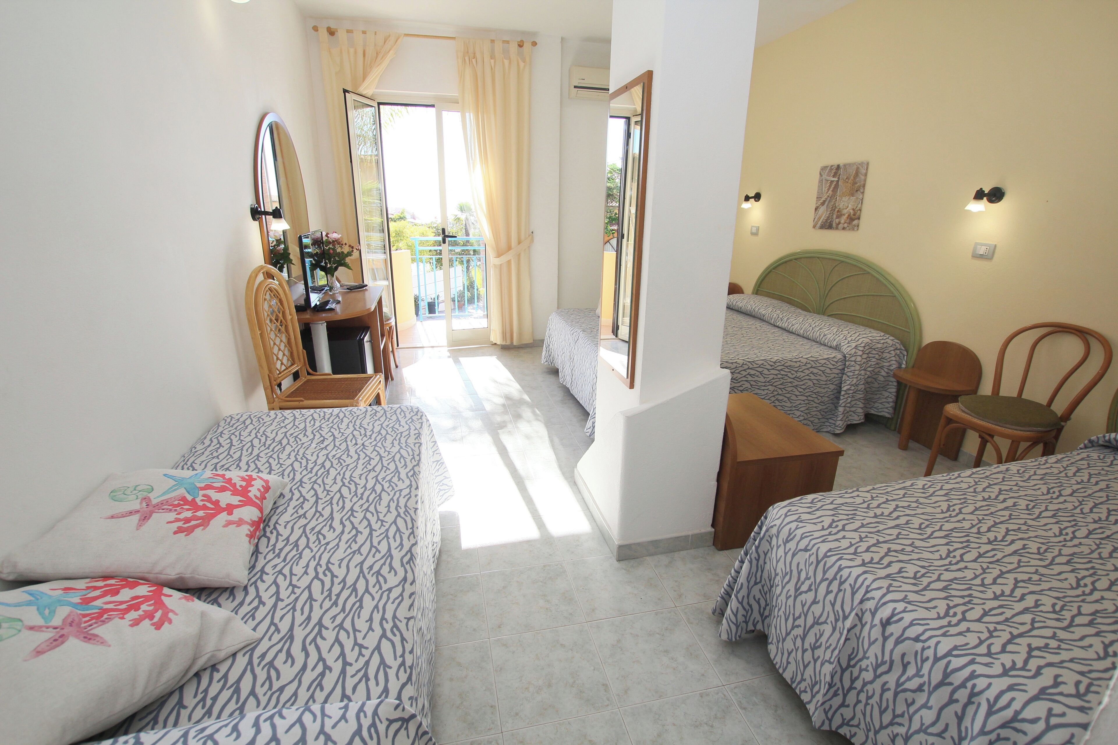 Una camera da letto con due letti, una scrivania, una sedia e un balcone con vista.