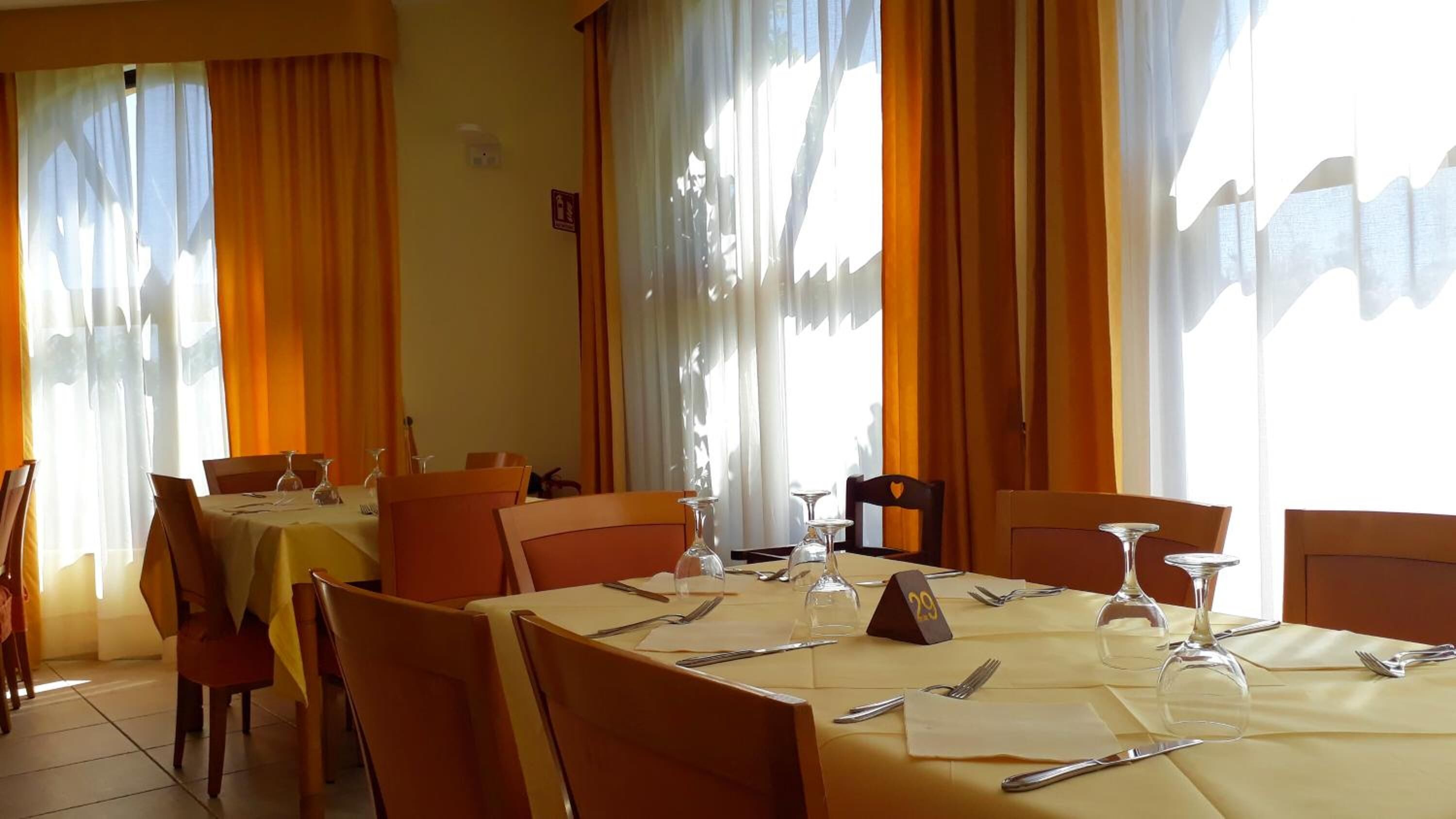 A dining area with tables set for four, each with cutlery and wine glasses.