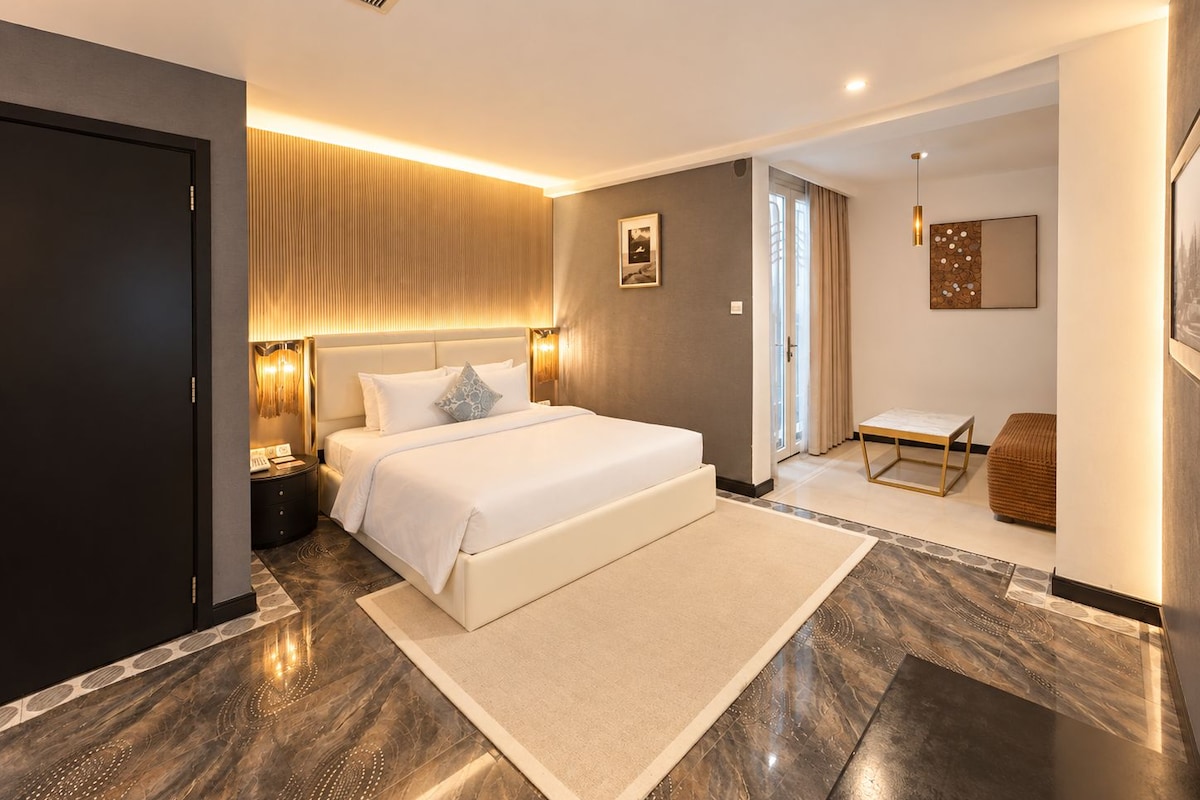 Een moderne hotelkamer met een groot bed, een nachtkastje, een stoel, een bureau en een badkamer met douche en toilet.
