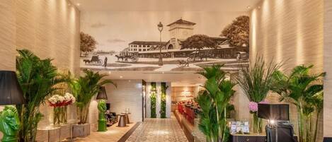 Un vestíbulo de hotel con un pasillo central, una recepción y un mural en la pared.