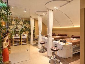 Een spa-ruimte met een massagetafel, een wastafel en een plank met toiletartikelen.