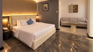 Een moderne hotelkamer met een groot bed, een slaapbank, een klein rond tafeltje en een wanddecoratie.