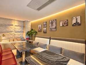 A modern interior with a marble dining table, cushioned seating, and framed photographs on the wall. - A&EM Ben Thanh Hotel (Ho Chi Minh City)