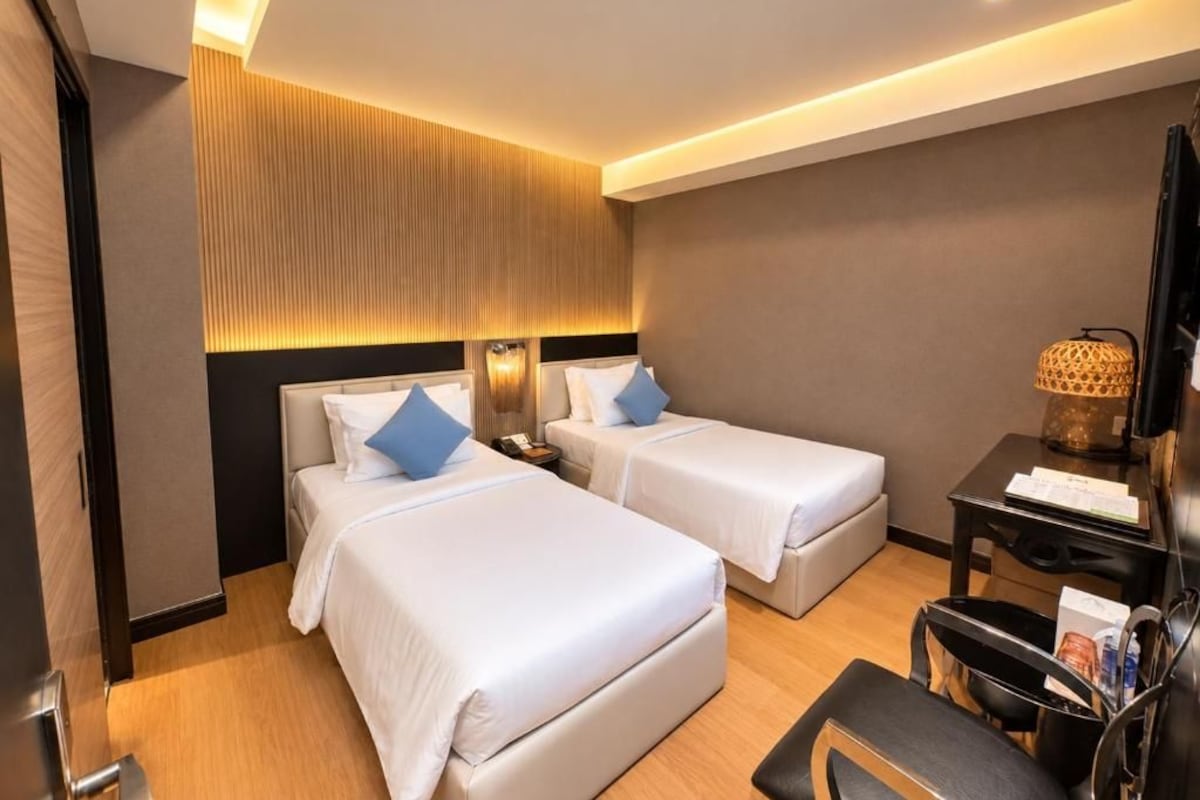 Een hotelkamer met twee bedden, een bureau en een stoel.