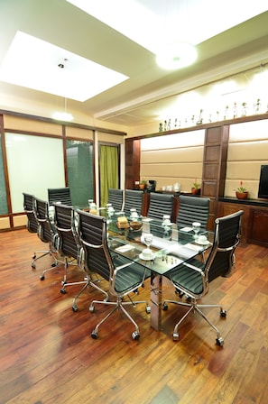 A conference room with a glass table, black chairs, wooden flooring, and a large window with curtains. - Cocoon Boutique Hotel (Quezon City)