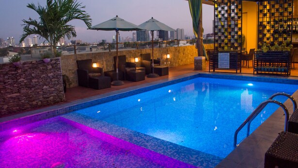A rooftop pool area with a view of the city skyline, seating arrangements, and a bar area. - Cocoon Boutique Hotel (Quezon City)
