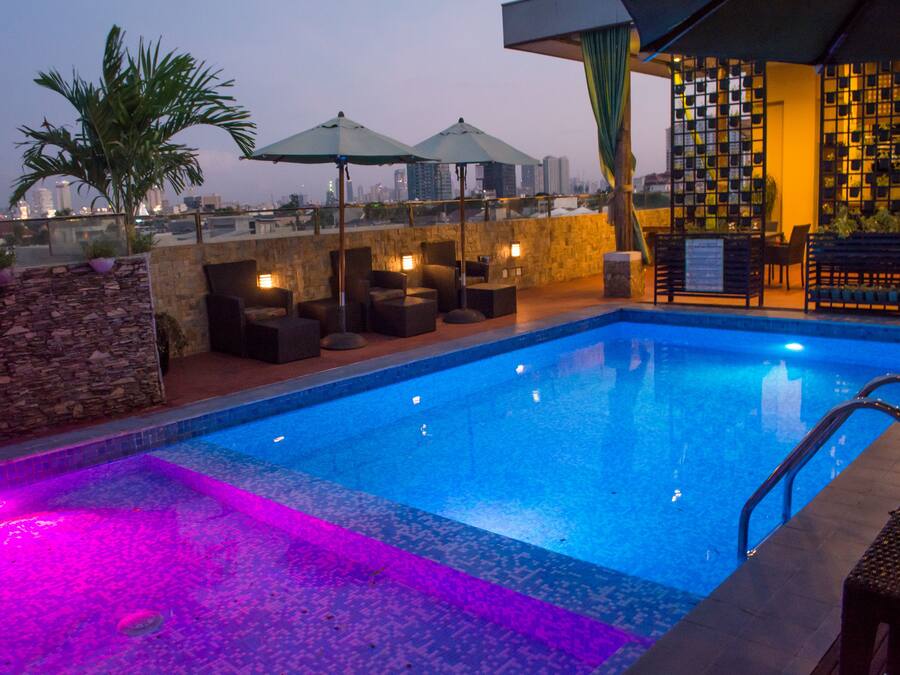 Una piscina al aire libre, sombrillas, sillones reclinables de piscina