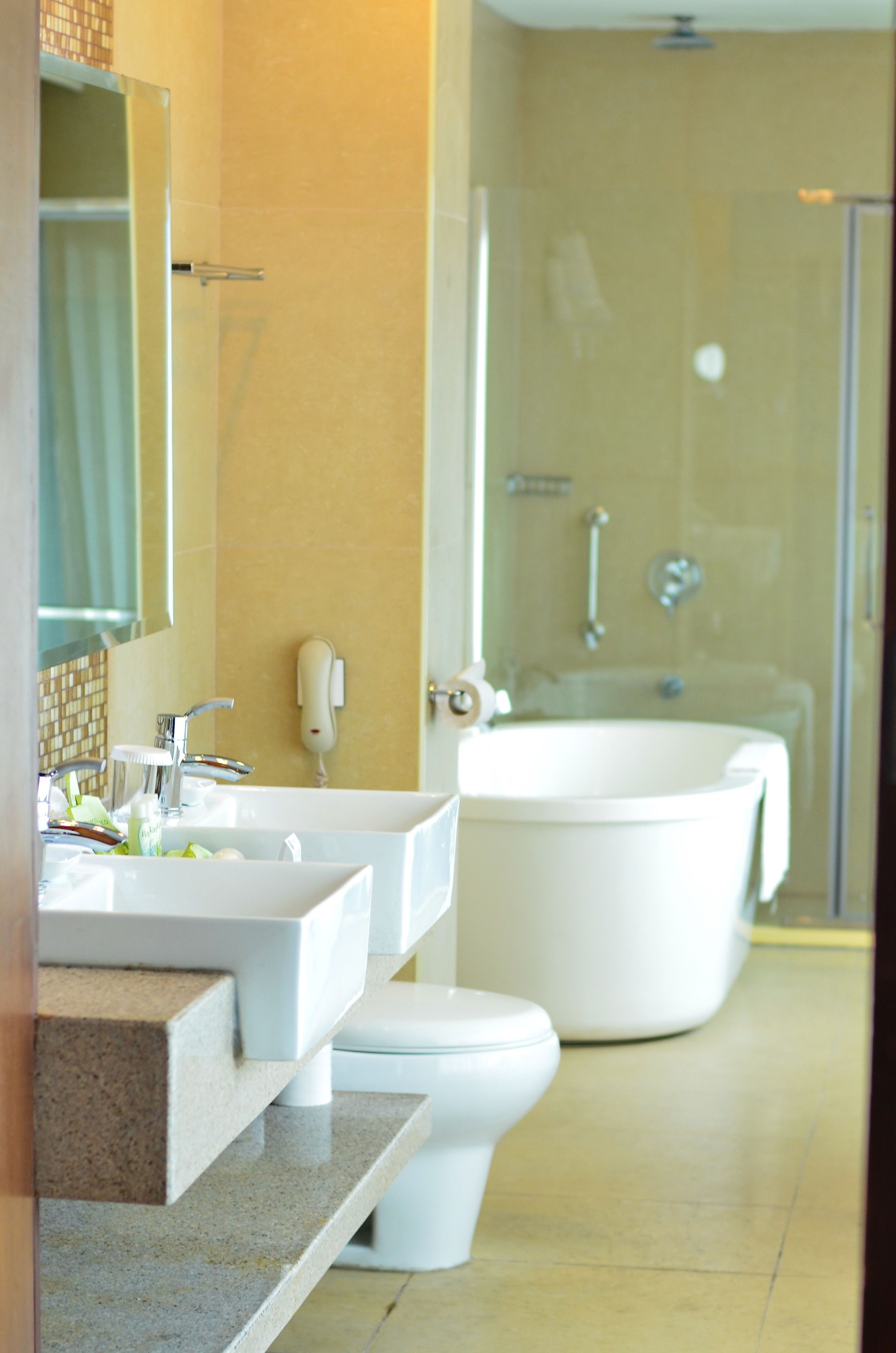 A modern bathroom with a large bathtub, two sinks, and a toilet.