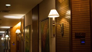 A hallway with wooden paneling, wall-mounted lamps, and framed artwork. - Cocoon Boutique Hotel (Quezon City)