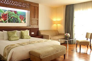 Una habitación de hotel con una cama grande, un sofá, una silla, una mesita de centro y un cuadro en la pared.