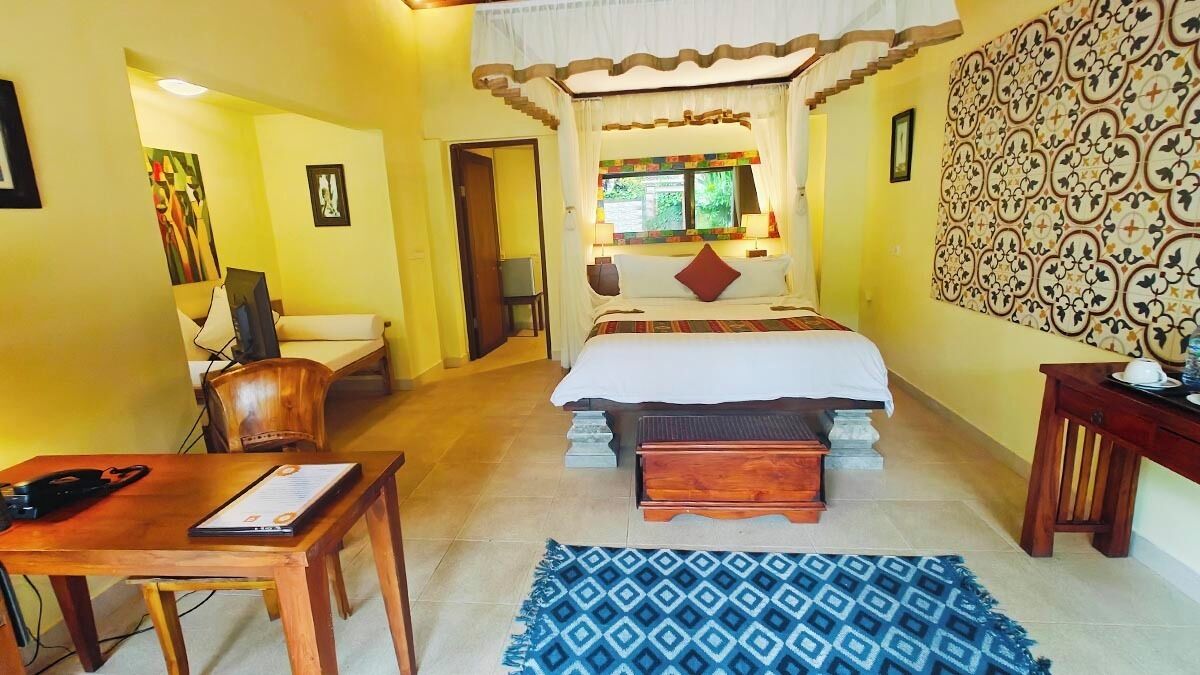 Una habitación de hotel con una cama, un escritorio, una silla, una mesita y una alfombra estampada.
