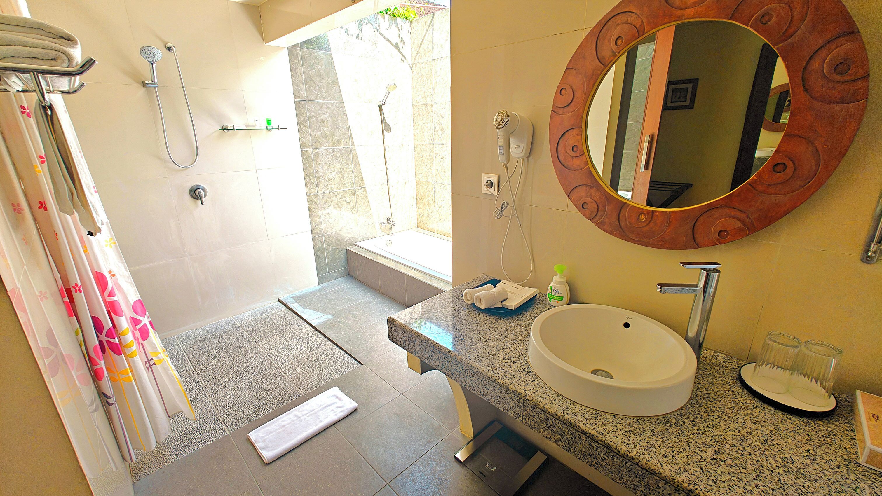 Une salle de bain équipée d’un lavabo, d’un miroir, d’une douche et d’un porte-serviettes.