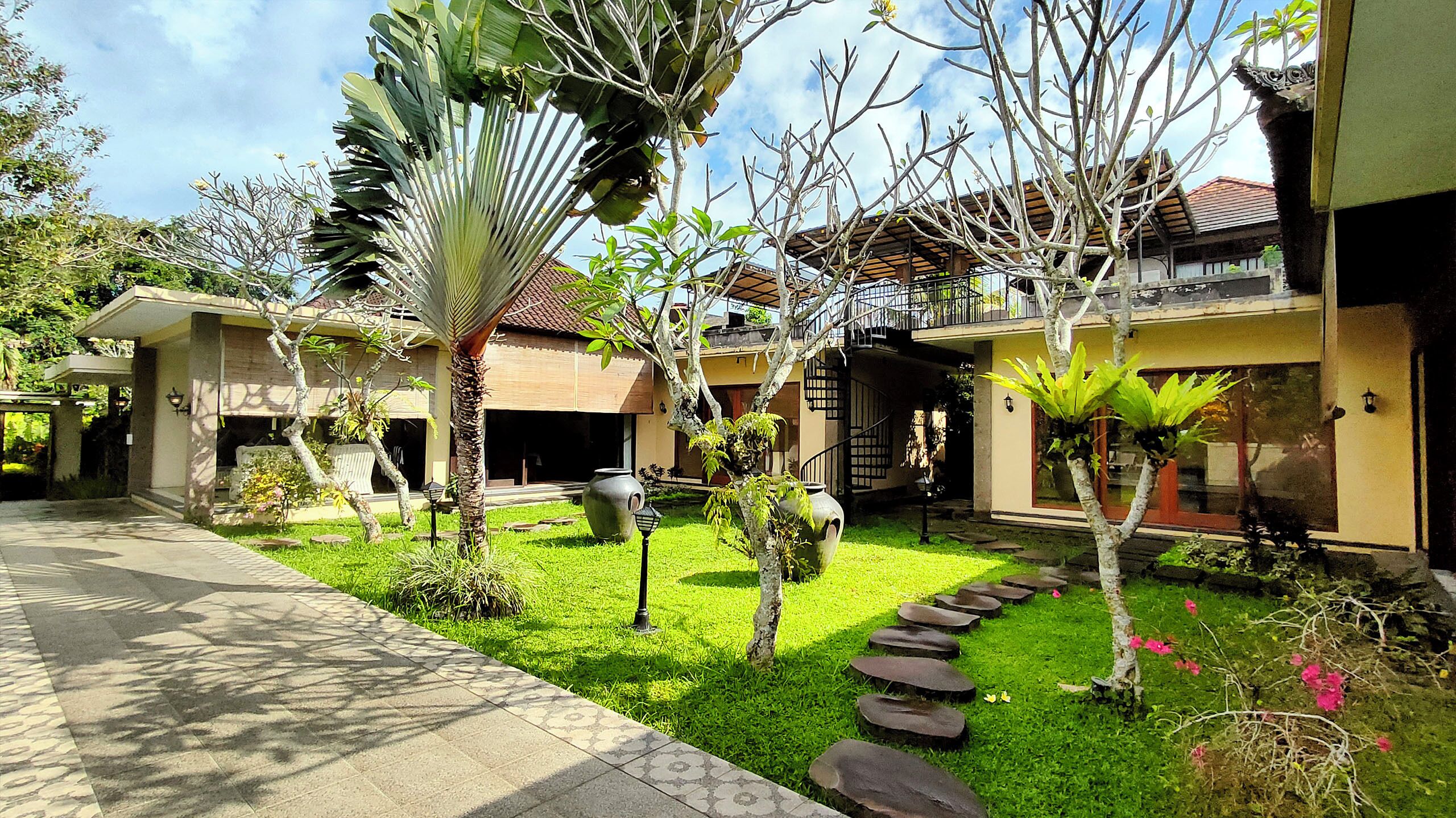 A residential property with a well-maintained garden, a paved driveway, and a two-story house with a tiled roof.