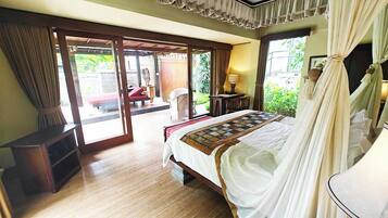 Un dormitorio con cama, mesita de noche, lámpara y vistas al exterior.