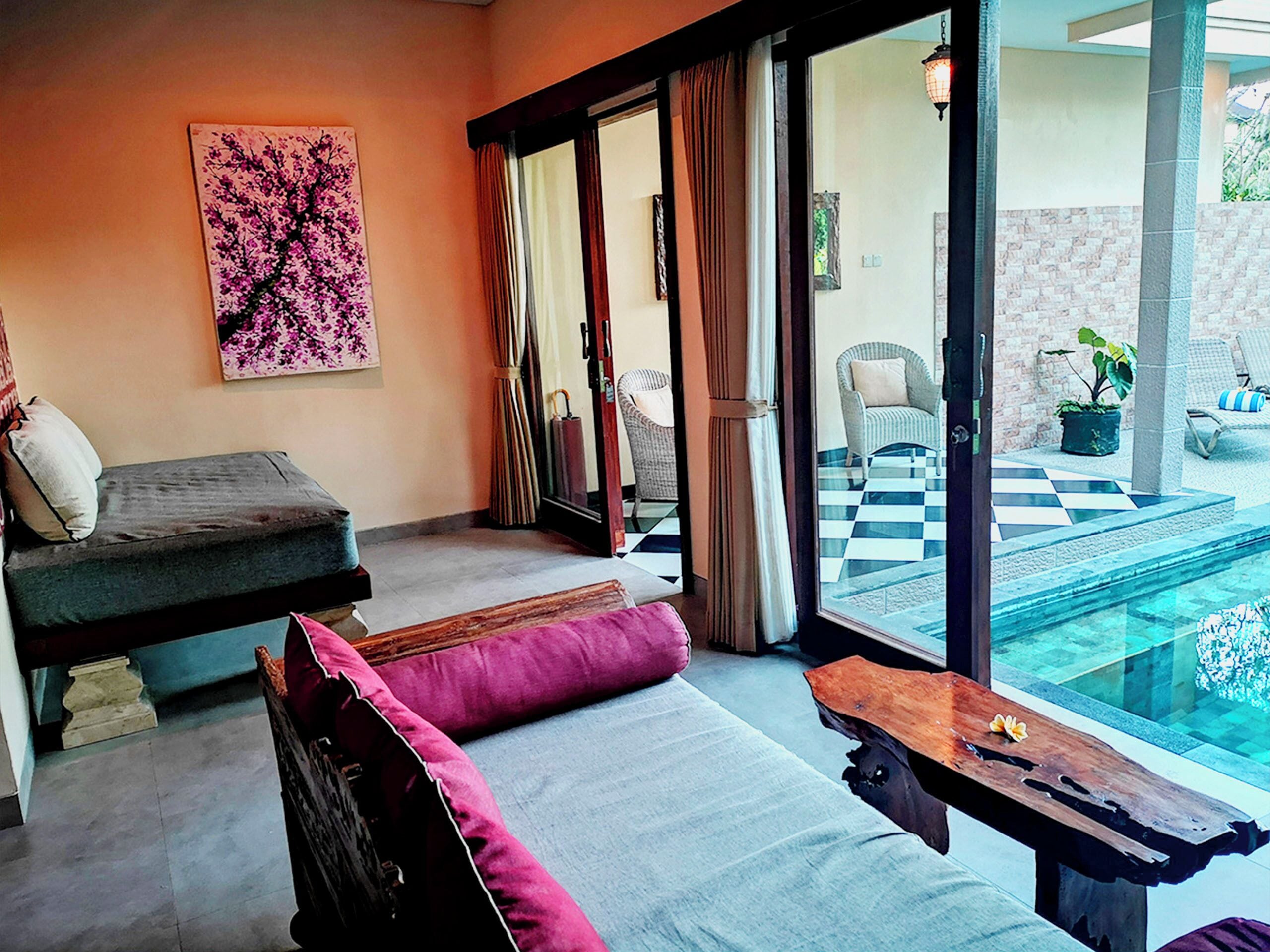 A modern room with a sofa, a wooden table, and a view of an outdoor pool area.