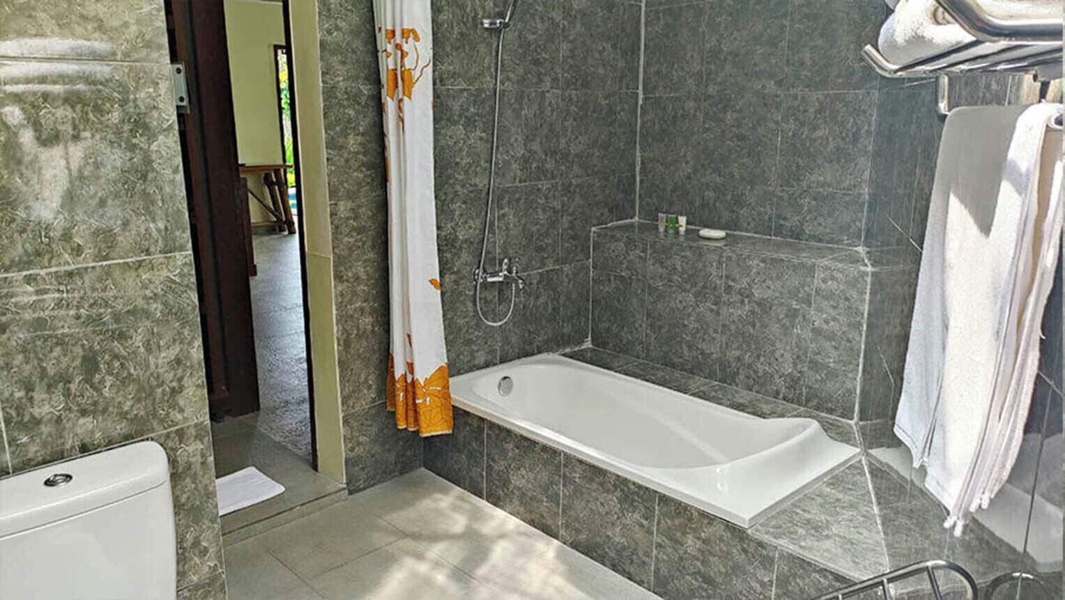 A modern bathroom with a bathtub, shower, and tiled walls.