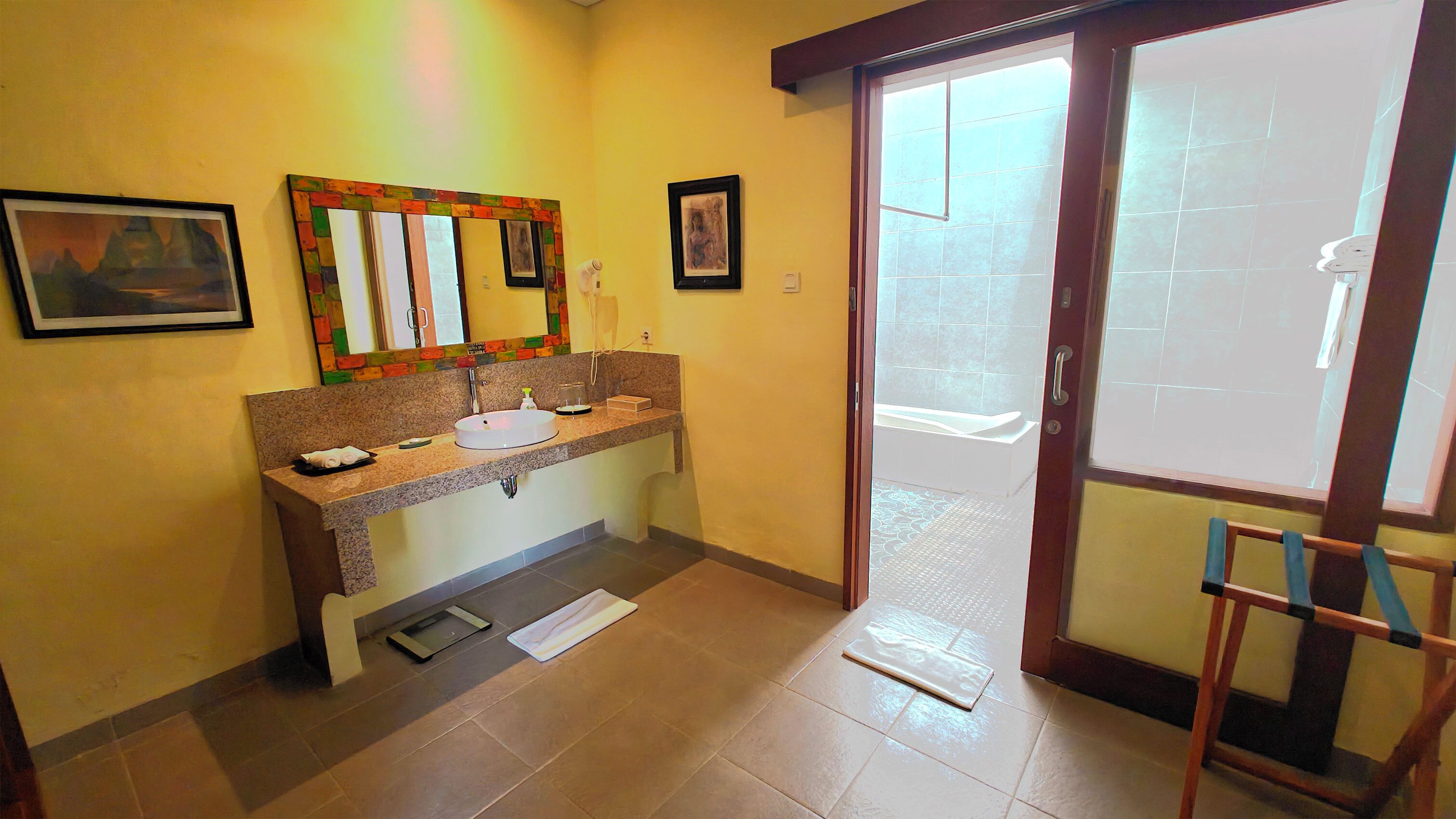 Baño con lavabo, espejo y perchero. Hay una puerta que da a un balcón.