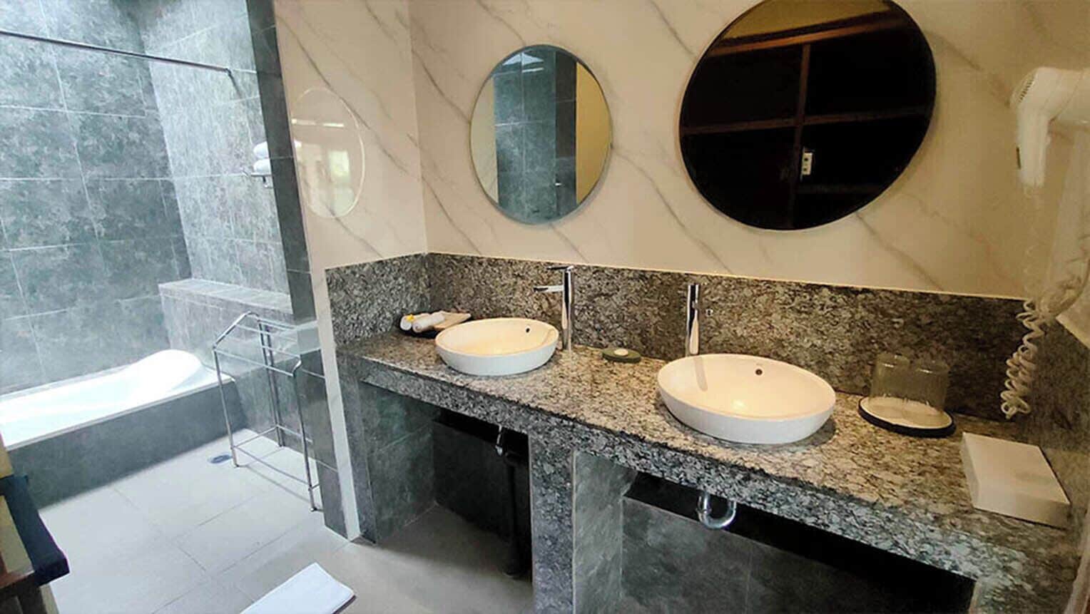 Ein modernes Badezimmer mit zwei Waschbecken, einem großen Spiegel und einer Duschkabine.