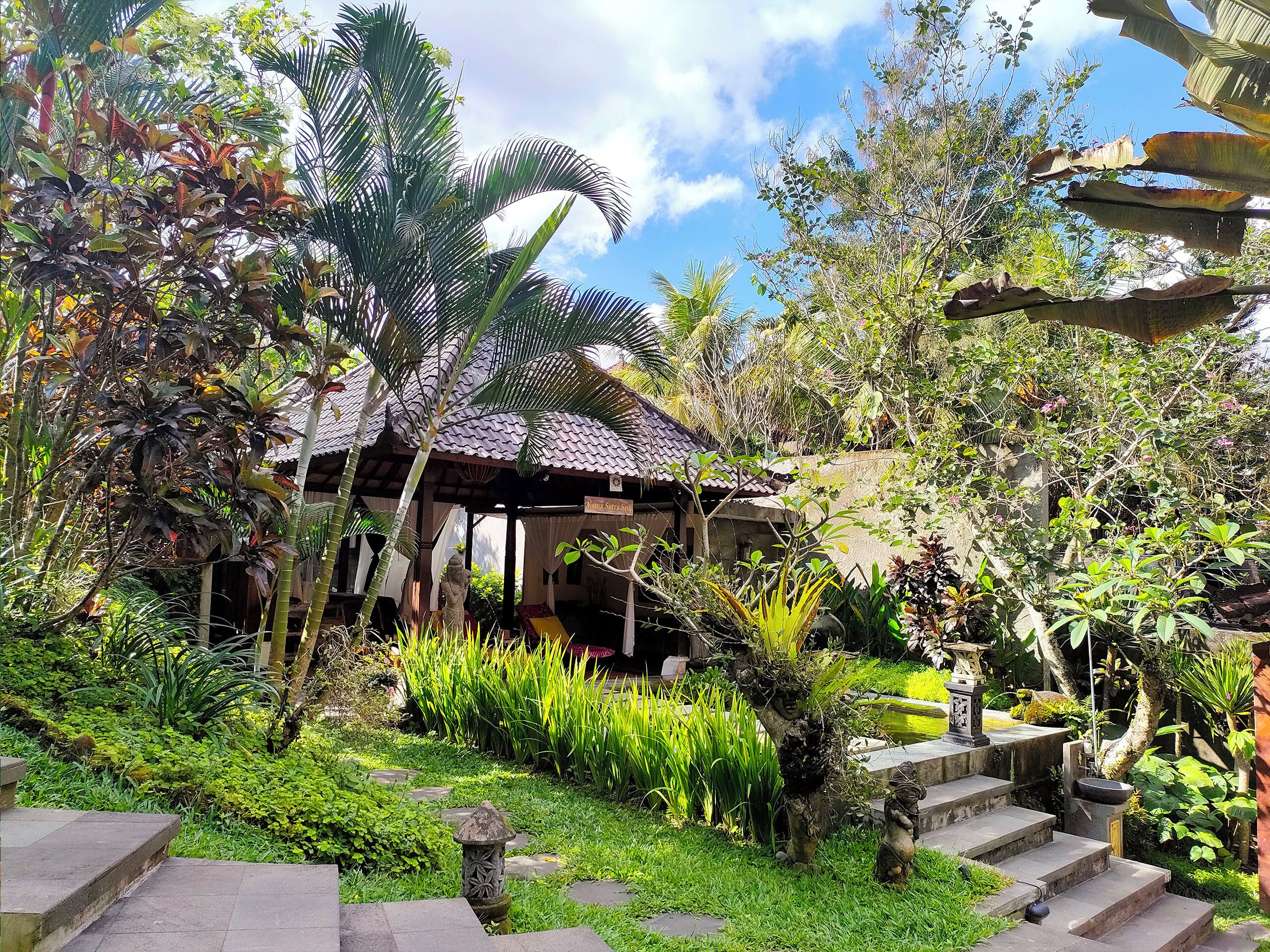 Un jardin agrémenté d’un belvédère, d’escaliers en pierre et de diverses plantes tropicales.