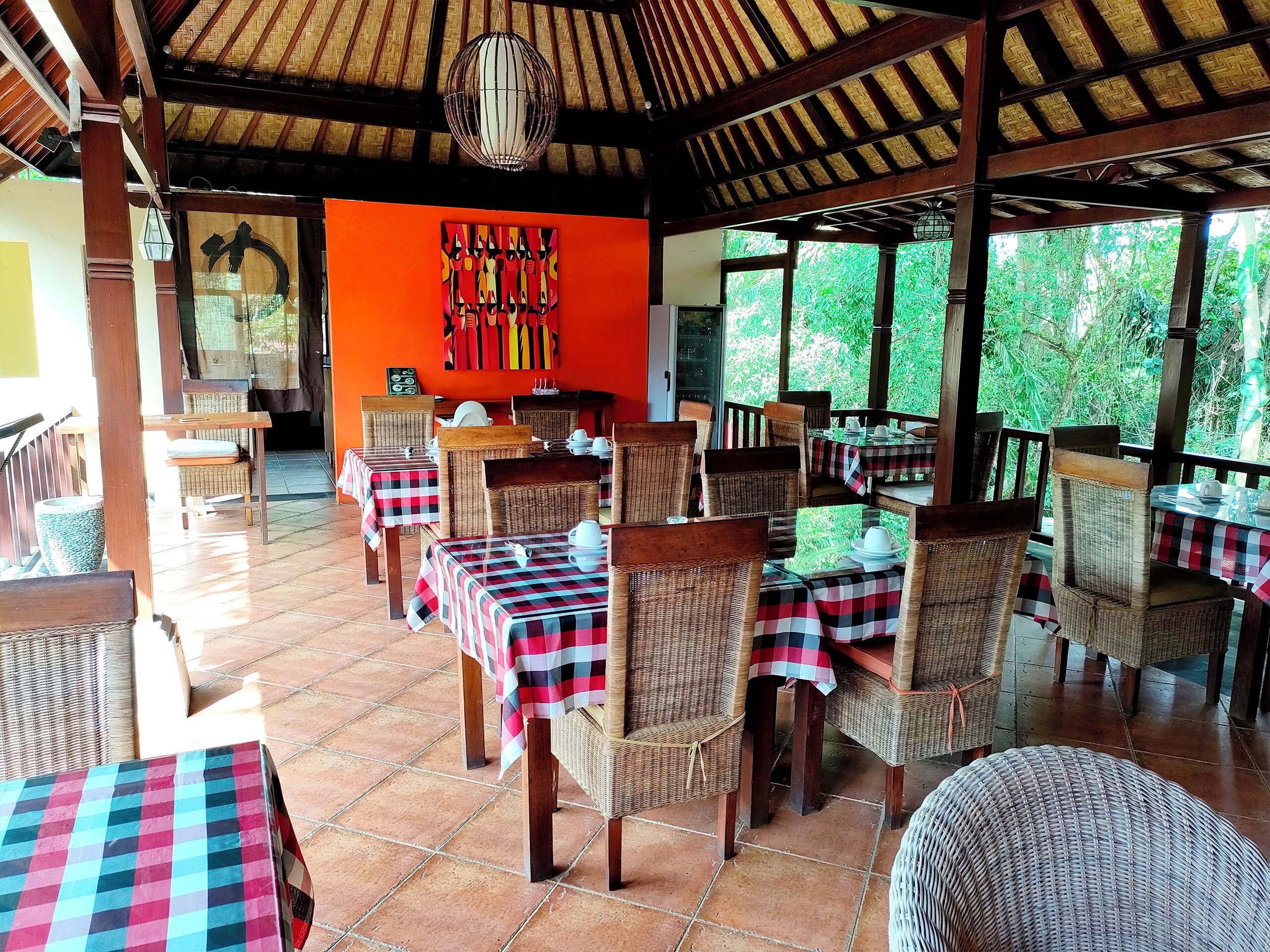 An outdoor restaurant with wicker furniture and checkered tablecloths.
