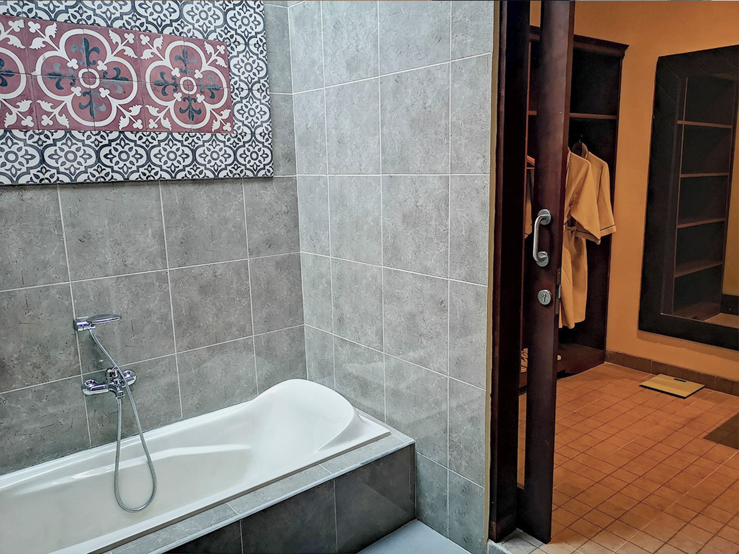 Un baño moderno con una bañera independiente, baldosas grises y un adorno decorativo en la pared.