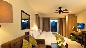 A hotel room with a bed, a desk, a television, a ceiling fan, and a window with curtains. - Azalea Hotels & Residences Baguio (Baguio)