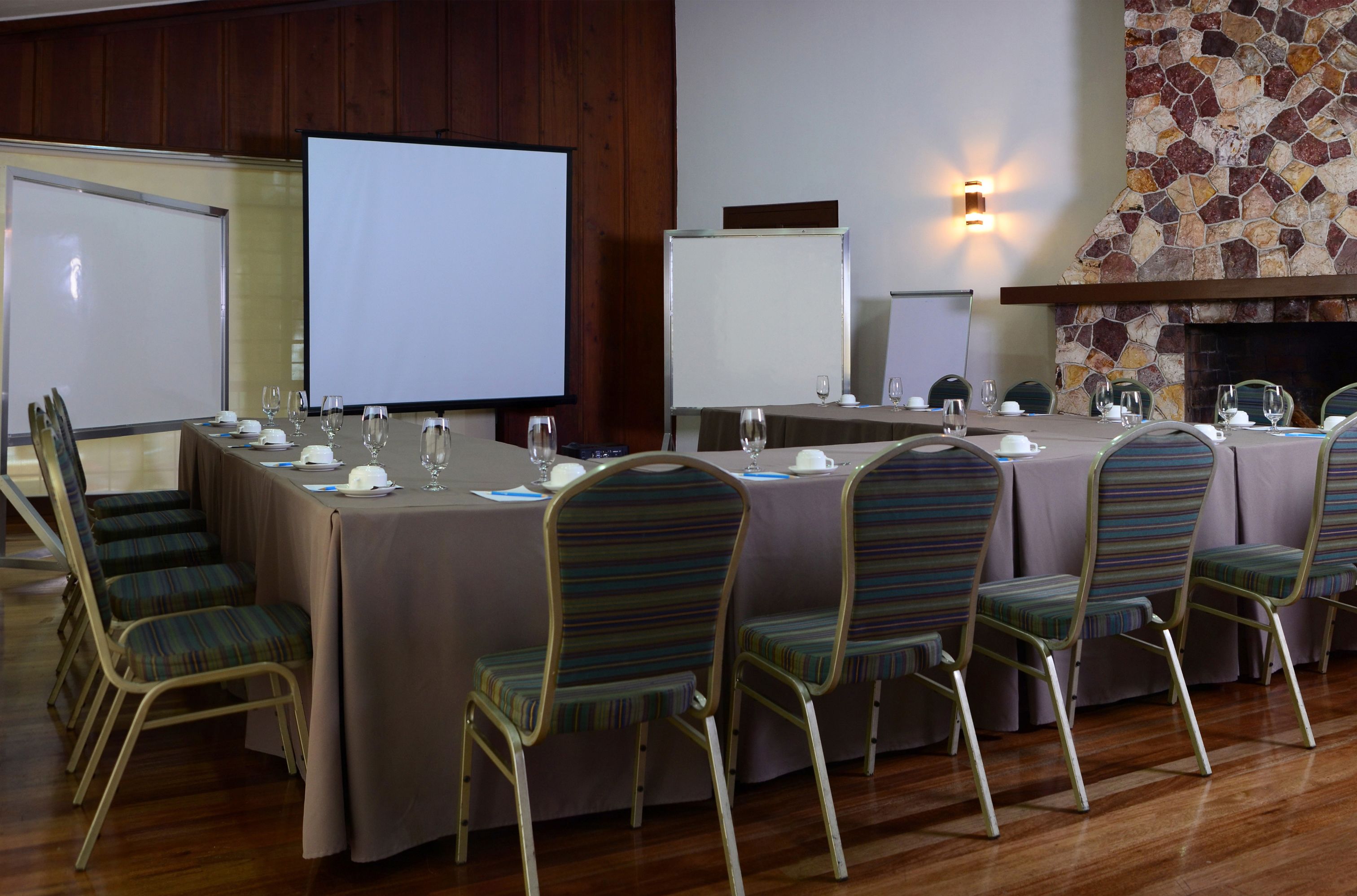 A conference room with a long table, chairs, a whiteboard, and a fireplace.