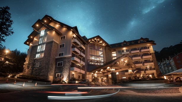 A multi-story hotel with a stone facade, balconies, and a starry night sky. - Azalea Hotels & Residences Baguio (Baguio)