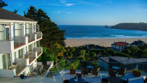 Un hotel frente al mar con balcón con vista a la playa, mobiliario exterior y vista al océano.