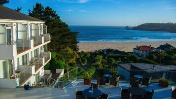Enjoy stunning ocean views from the hotel's spacious outdoor seating area with tables and chairs.
