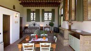 A cozy dining area with a wooden table and chairs, a sofa, and a fireplace. - Agriturismo Il Casolare di Bucciano (San Gimignano)